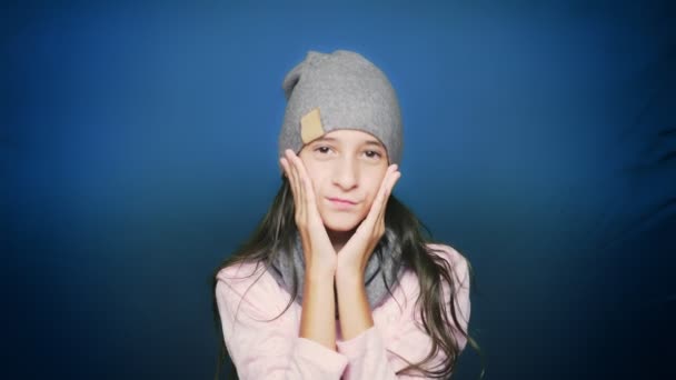 Schönes Teenie-Mädchen in Herbstkleidung posiert vor der Kamera vor blauem Hintergrund — Stockvideo