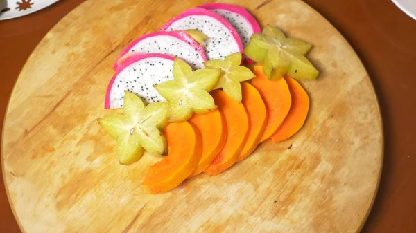 exotic fruits on the table. carambola and dragon fruit, papaya, passion fruit, fruit cut into pieces, on a cutting board