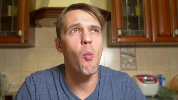 a man eats an apple strudel with pleasure, sitting in his kitchen.