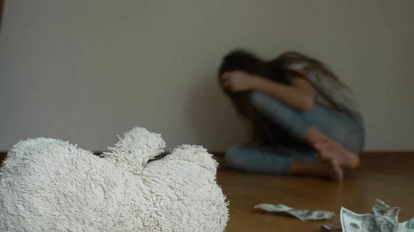 Uma criança desesperada em depressão senta-se na parede de seu quarto, tenta tentar suicídio. ao lado dele é um brinquedo macio abandonado — Fotografia de Stock