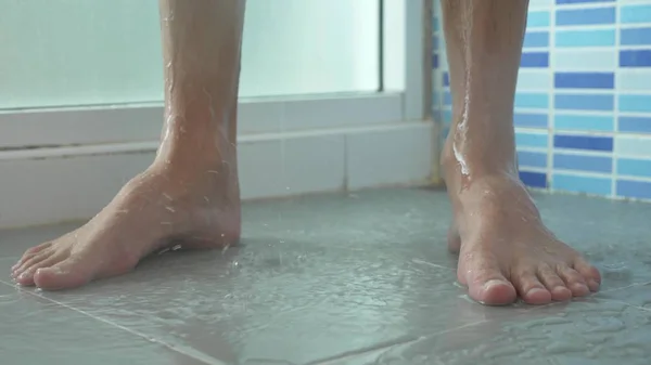 Крупним планом чоловічі ноги в душі. молодий чоловік приймає душ . — стокове фото