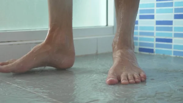 Крупним планом чоловічі ноги в душі. молодий чоловік приймає душ . — стокове фото