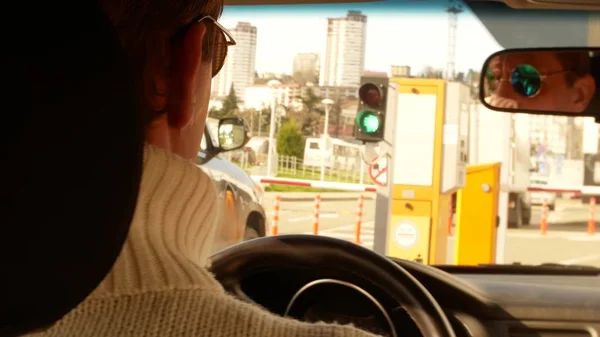 La mano di un uomo guida una macchina. passaggio attraverso la barriera. uscita dal parcheggio coperto. sfocatura sfondo . — Foto Stock