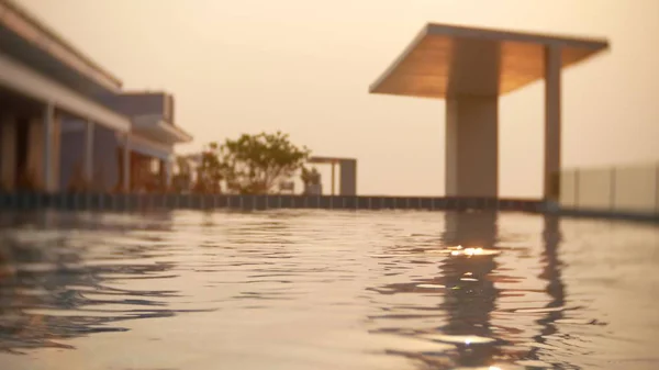 En lyxig pool på taket av huset med utsikt över havet. På solnedgången. Solar bländning på vattnet. bakgrundsoskärpa — Stockfoto