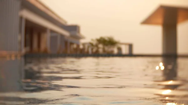 Uma piscina luxuosa no telhado da casa com vista para o mar. Ao pôr-do-sol. brilho solar na água. borrão de fundo — Fotografia de Stock