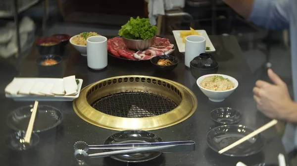 Еда в булгоги, корейское барбекю, в ресторане. приготовление пищи в китайском ресторане на столе гриль барбекю, крупным планом — стоковое фото