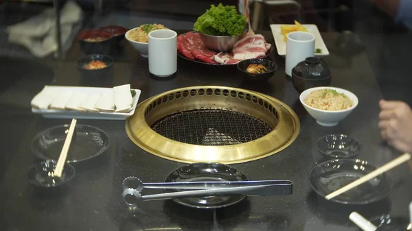 Comida em bulgogi, churrasco coreano, no restaurante. cozinhar no restaurante chinês na mesa grelhar churrasco, close-up — Fotografia de Stock