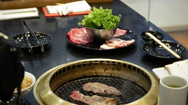 Comida em bulgogi, churrasco coreano, no restaurante. cozinhar no restaurante chinês na mesa grelhar churrasco, close-up — Fotografia de Stock