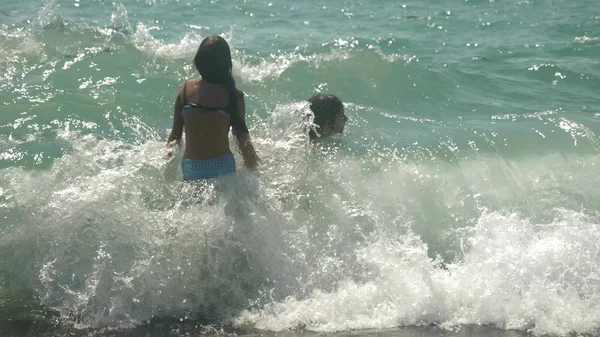 Glückliche Kinder springen in die Wellen des Meeres. — Stockfoto