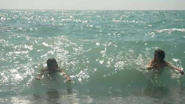 Crianças felizes estão pulando para as ondas do mar . — Fotografia de Stock