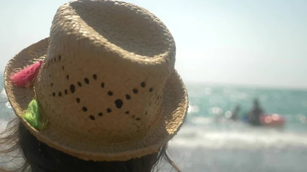 클로즈업입니다. 밀 짚 모자에 소녀는 바다의 파도에 보인다. 후면 모습 — 스톡 사진