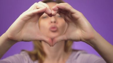 Diş Bakımı ve diş beyazlatma. Diş Hekimliği ve kozmetik. Arka planda bir bulanık görüntü gülümseyen kadın. bir kız elinde keskinlik bir kalp işareti gösteriyorlar. renk arka plan