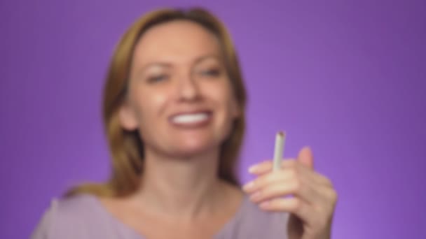 Lachende meisje. trekt een sigaret met de nadruk op de voorgrond aan het licht. achtergrondkleur — Stockvideo
