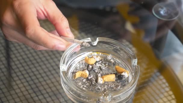 Cigaretové nedopalky od skla popelník na skleněný stůl venku. — Stock video