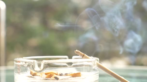 mégots de cigarette à partir d'un cendrier en verre sur une table en verre à l'extérieur .