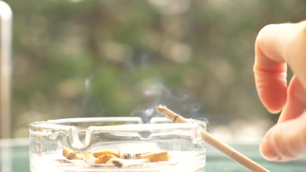 mégots de cigarette à partir d'un cendrier en verre sur une table en verre à l'extérieur .