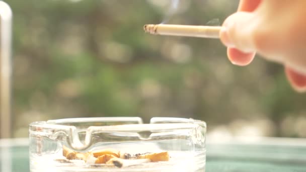 mégots de cigarette à partir d'un cendrier en verre sur une table en verre à l'extérieur .