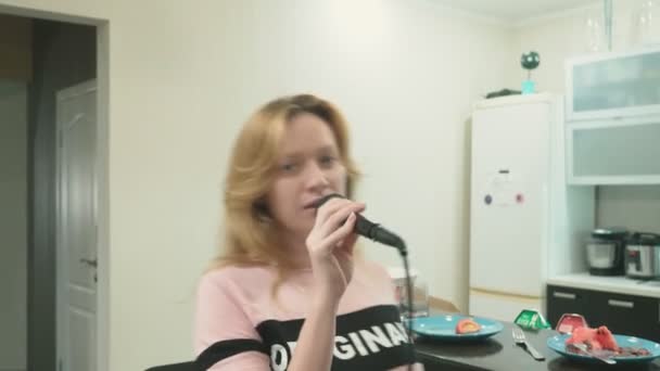 Close-up. vrouw zingen karaoke in de microfoon thuis. achtergrond vervagen — Stockvideo