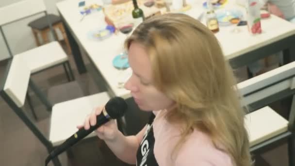 Close-up. vrouw zingen karaoke in de microfoon thuis. achtergrond vervagen — Stockvideo