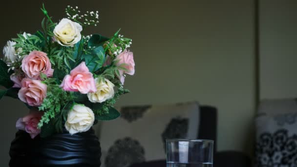 Nahaufnahme, ein Strauß Rosen und ein Glas reines Wasser auf dem Tisch — Stockvideo