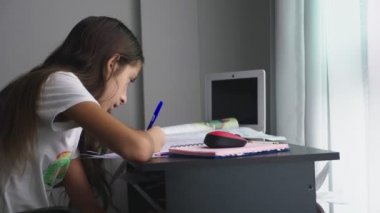 Genç kız masanın üstünde onun odasına okul için ödev