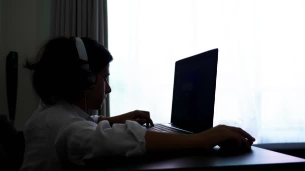 Teenager plays video games. Computer teenager boy with headphones looking at laptop screen — Stock Video