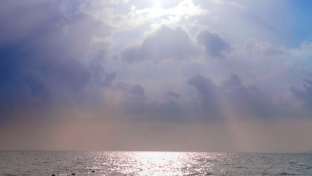 Сонце світить крізь красиві білі хмари над морем . — стокове відео