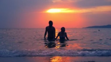 siluetleri, Çift, erkek ve kadın üzerinde deniz deniz manzarası, kırmızı dramatik günbatımı arka planı elele denizden. Güneş deniz kırmızı renkler.