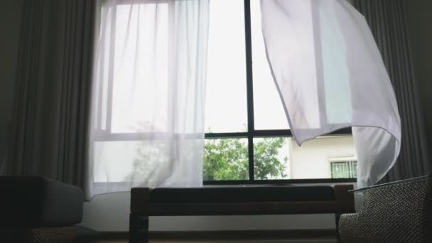 Transparant venster gordijn, voorzichtig bewogen door de wind. buiten het venster ziet u dat de groene bladeren van de bomen — Stockvideo