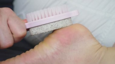 ayak ve pedikür Ponza araçları ve bir fırça kullanarak topuklar üzerinde kuru ciltler için bakım.