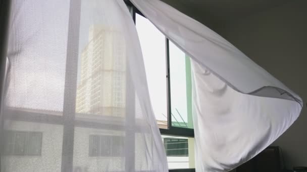 Transparent window curtain, gently moved by the wind. outside the window you can see the skyscrapers — Stock Video