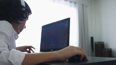 Genç video oyunları oynuyor. Dizüstü bilgisayar ekranına bakarak kulaklık ile bilgisayar genç çocuk