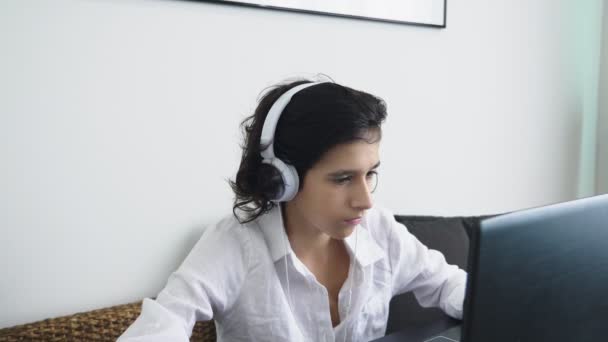 Підліток грає у відеоігри. Комп'ютерний хлопчик-підліток з навушниками дивиться на екран ноутбука — стокове відео