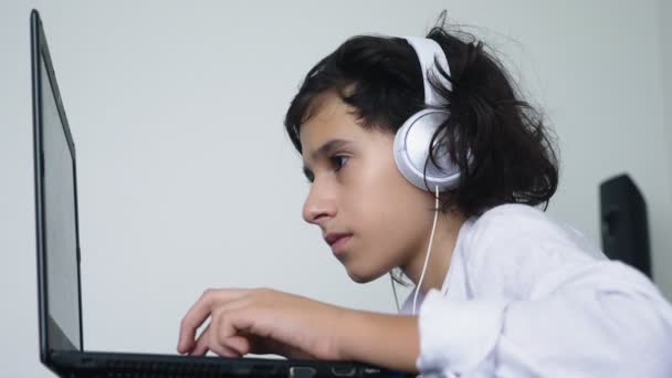 Adolescente joga videogames. Computador adolescente menino com fones de ouvido olhando para a tela do laptop — Vídeo de Stock