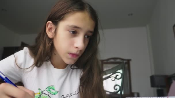 Дівчина-підліток робить домашнє завдання для школи в її кімнаті, на столі — стокове відео