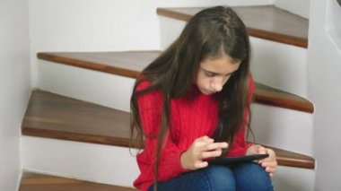 Güzel kız kırmızı bir kazak ve terry çorap ve kot, merdivenlerde, oturan tablet kullanır
