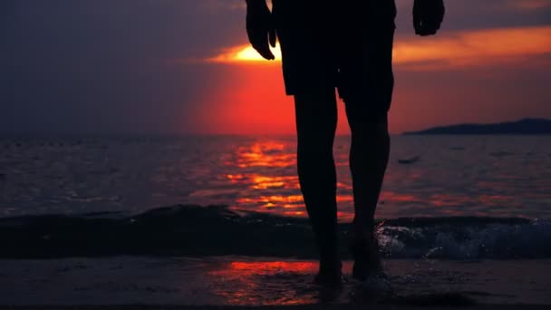 Silueta de un hombre en forma que emerge del mar contra el telón de fondo del paisaje marino, una puesta de sol dramática roja en el mar el sol pinta el mar rojo . — Vídeos de Stock