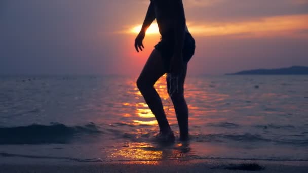 Silhouet van een fit man die uit de zee tegen de achtergrond van het landschap van de zee, een rode dramatische zonsondergang aan zee de zon schildert de zee rood. — Stockvideo