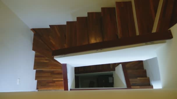 Top view of a modern staircase with brown wooden steps and white walls. three flights of stairs. — Stock Video