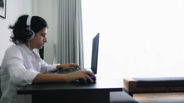 Genç video oyunları oynuyor. Dizüstü bilgisayar ekranına bakarak kulaklık ile bilgisayar genç çocuk