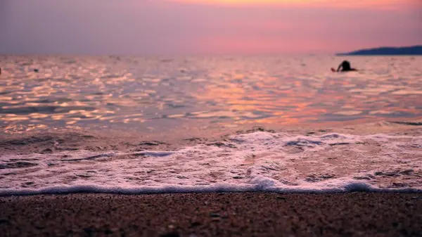 Σιλουέτες, άνθρωποι κολύμπι στη θάλασσα με φόντο το εντυπωσιακό ηλιοβασίλεμα τοπίο, κόκκινη θάλασσα, στη θάλασσα τον ήλιο χρωματίζει τη θάλασσα με κόκκινο χρώμα. — Φωτογραφία Αρχείου