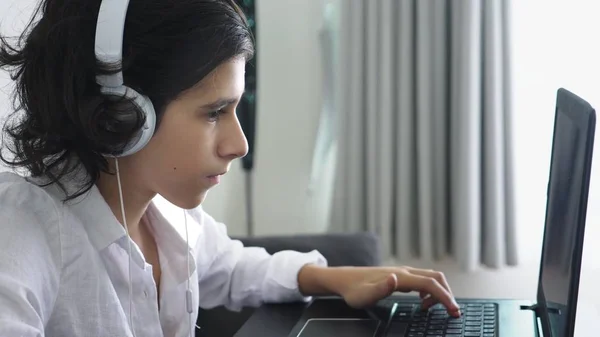 Підліток грає у відеоігри. Комп'ютерний хлопчик-підліток з навушниками дивиться на екран ноутбука — стокове фото