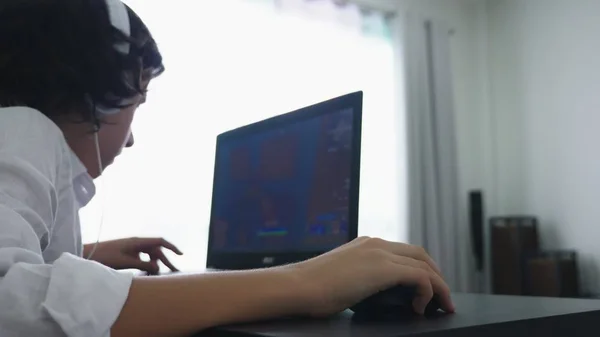 Підліток грає у відеоігри. Комп'ютерний хлопчик-підліток з навушниками дивиться на екран ноутбука — стокове фото
