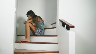 Sorun evde bir mandalina onun elinde tutan bir modern Merdiven Merdiven üzerinde oturan üzgün kız güzel