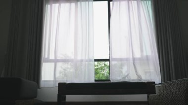 Saydam pencere perde, yavaşça rüzgar tarafından taşındı. Pencerenin dışında yeşil ağaçların yaprakları görebilirsiniz