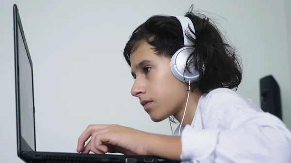Teenager plays video games. Computer teenager boy with headphones looking at laptop screen