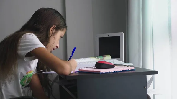 Дівчина-підліток робить домашнє завдання для школи в її кімнаті, на столі — стокове фото