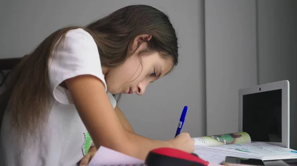 十几岁的女孩在她的房间里, 在桌子上为学校做作业 — 图库照片