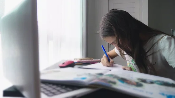 Девочка-подросток делает домашнее задание для школы в своей комнате, на столе — стоковое фото