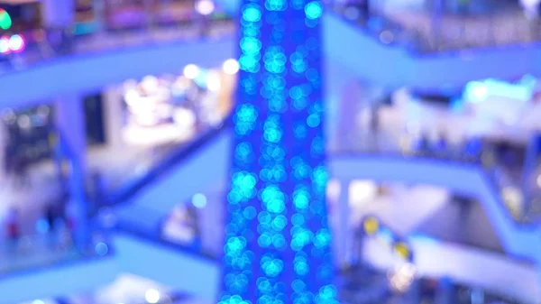 El concepto de compras navideñas. Blur hall en un enorme centro comercial moderno con un montón de escaleras mecánicas y un árbol de Navidad — Foto de Stock